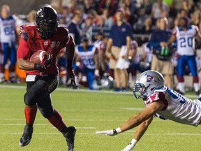 Ottawa RedBlacks RB Jeremiah Johnson eludes the tackle of Montreal Alouettes Aaron Lavarias during CFL action at TD Place on Friday September 26, 2014. Errol McGihon/Ottawa Sun files