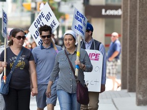 CUPE 101 picketers walk along Richmond Street with signs near Market Tower, where some union members are employed at an Ontario Works office, as they continue their strike in London, Ont. on Tuesday June 2, 2015. About 750 CUPE 101 members are currently on strike including Ontario Works and inside city hall workers.  Craig Glover/The London Free Press/Postmedia Network