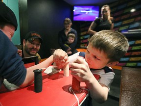 Six-year-olds Kayden (right) and Ryley battle at the kids table as vice-president Jim Findley and other members look on during a Manitoba Arm Wrestling Association practice at Little Bones Wings, in the basement of Transcona's Royal George Hotel, in Winnipeg on May 6, 2015. (Kevin King/Winnipeg Sun)