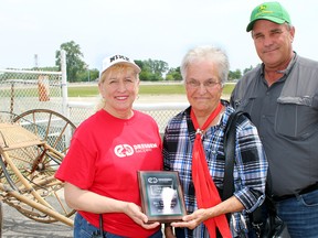 Opening day of the 2015 Dresden Raceway season included a special dedication by Dresden Agricultural Society president Lucille Laprise, left, of a sulky built in the town during the 1880s. Ethel Townsend, middle, flanked by her son David, donated the antique sulky to the society in memory of her husband Bill for generations of race fans to enjoy for years to come on Sunday June 7, 2015 in Chatham, Ont. (Vicki Gough/Chatham Daily News/Postmedia Network)