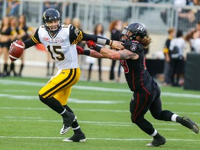 Hamilton Tiger-Cats QB, Jeff Mathews, fights off Ottawa RedBlacks,Travis Brown, seconds before throwing first touchdown pass, at Tim Hortons Field on Monday night. (Dave Thomas/Toronto Sun/Postmedia Network)