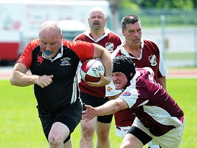 Belleville Bulldogs ballcarrier Taguen Christie breaks free from Kawartha Krocks defenders during over-35s Old Boys rugby action Sunday at MAS Park. (Don Carr for The Intelligencer)