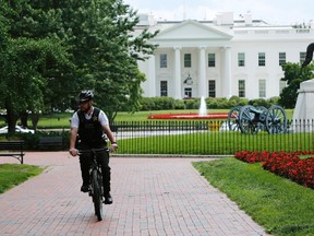 A U.S. Secret Service uniformed police officer peddles in Lafayette Square during a bomb threat at the White House in Washington June 9, 2015. The U.S. Secret Service cleared the White House briefing room on Tuesday after a bomb threat was called into local police, prompting an evacuation. No other areas of the White House were affected, and the briefing room was checked and cleared.  REUTERS/Gary Cameron