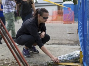 Cheryl Gavin leaves a bouquet of roses at the scene where police officer Daniel Woodall was shot and killed, in Edmonton June 9, 2015. Constable Woodall was killed and another officer Sergeant Jason Harley injured on Monday in Edmonton, Canada after an exchange of fire with a suspect, police said. The officers were attempting to arrest the suspect on Monday evening, when the shootings happened, police said. REUTERS/Topher Seguin