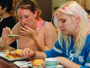 Megan Major-Thompson, left, and Makayla Van Riel, both Grade 8 students at Frontenac Public School, enjoy the fruits of their labour after spending the morning making burgers, french fries and all the fixings at Burger Club, held at Essence Restaurant at St. Lawrence College. The pilot program is an extension of the Enactus St. Lawrence College’s Slow Cookers for Kids program that looks to teach food and financial literacy to youth in a new way. (Julia McKay/The Whig-Standard)