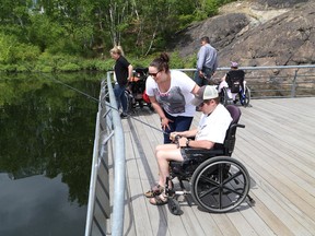 Rehab worker and service attendant Jenna Latendre helps Tyler Lamothe with his fishing during an outing with the March of Dimes Wade Hampton House on the boardwalk near Science North in Sudbury, Ont. on Tuesday June 9, 2015. John Lappa/Sudbury Star/Postmedia Network