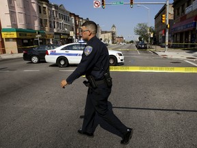 A Baltimore police officer attempts to secure a crime scene with tape at the scene of a shooting at the intersection of West North Avenue and Druid Hill Avenue in West Baltimore, Maryland May 30, 2015. Local media have reported more than 35 murders in the city of Baltimore since the April rioting over the death of 25-year-old resident Freddie Gray and shootings continue regularly in his West Baltimore neighborhood.  REUTERS/Jim Bourg