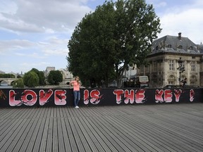 A woman stands in front of a panel painted with the words ' Love is the Key!' set up on the railings of the Pont des Arts on June 10, 2015 in Paris after padlocks were removed from the bridge. AFP PHOTO / THOMAS OLIVIA