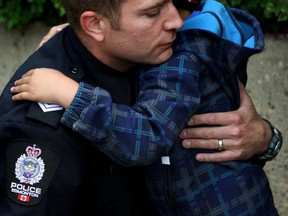 Getting a big blue hug. 5-year-old Isiah Rain was with a group that stopped at Edmonton Police Services Headquarters on Friday, June 12, 2015 and presented Sgt. Steve Sharpe with flowers and two hand painted rocks coloured like police cruisers with the words "EPS Strong" written on top to pay their respects for Cst. Daniel Woodall, killed in the line of duty on Monday. Claire Theobald/Edmonton Sun
