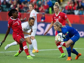 Erin Nayler, right, makes a save with Team Canada's Kadeisha Buchanan, No. 3, and Lauren Sesselmann, No. 10, in close. Nayler gave New Zealand its first shutout in World Cup play on Thursday. (David Bloom, Edmonton Sun)