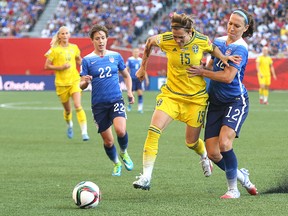 Sweden midfielder Therese Sjogran (centre) vies for the ball with United States midfielder Lauren Holiday (right) as Meghan Klingenberg closes in during the FIFA Women's World Cup Canada 2015 in Winnipeg on Fri., June 12, 2015. Kevin King/Winnipeg Sun/Postmedia Network