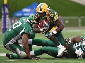 Edmonton Eskimos running-back Shakir Bell runs between Saskatchewan Roughriders #0 Alex Hall and #93  Tearrius George during the Northern Kickoff pre-season game at SMS Equipment Stadium in Fort McMurray on Saturday June 13, 2015.  Dale MacMillan/Edmonton Sun