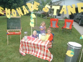 Sisters Marie, Bethany and Leah Lalonde wait for business, at their homemade lemonade stand on Mt. Pleasant Drive, during the annual town-wide yard sale held on Saturday.