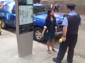 A parking officer tickets a City of Toronto truck installing a wayfinding map at King and Bay Sts. on Monday June 15, 2015. (Mike Strobel/Toronto Sun)