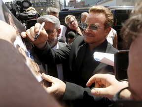 U2 lead singer Bono signs autographs while arriving for meetings on Parliament Hill in Ottawa, Canada, June 15, 2015. REUTERS
