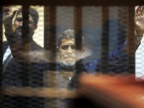 Deposed Egyptian President Mohamed Mursi greets his lawyers and people from behind bars after his verdict at a court at the outskirts of Cairo, Egypt, on June 16, 2015. (REUTERS/Asmaa Waguih)