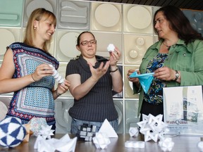 Math Quest: Queen’s Math Camp for Girls instructors Asia Zolnierczyk, left, and Yuliya Nesterova, with camp director Siobhain Broekhoven, show off some of some paper puzzles Nesterova made by using math to help promote the math summer camp held at Queen's University campus this August. (Julia McKay/The Whig-Standard)