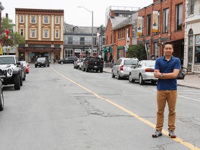 David Tran, director of the Sydenham Street Revived team, stands in the middle of Sydenham Street in downtown Kingston. Tran and his team are looking to the public for help in coming up with design ideas for their proposed pop-up park on Sydenham Street between Queen and Princess streets. (Julia McKay/The Whig-Standard)