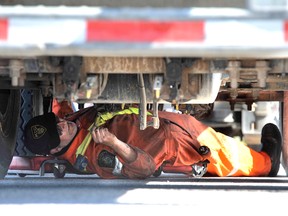 An officer with the Ministry of Transportation inspects the underside of a tractor trailer.
Mark Wanzel/Photo