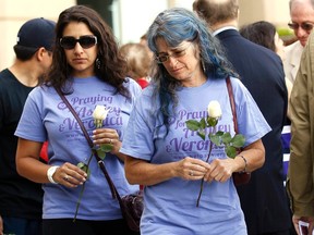 Women wearing shirts in support of victims Ashley Moser, who was left paralyzed during the Aurora theater shooting, and her daughter Veronica Moser-Sullivan, who was killed in the shooting, prepare to leave roses at a memorial during a ceremony marking the one-year anniversary of the tragedy in Aurora, Colorado July 20, 2013.  REUTERS/Rick Wilking
