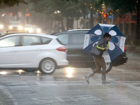 A pedestrian crosses the street as rain falls on downtown Fort Worth, Texas, on Wednesday, June 17, 2015. A churning tropical storm has caused little damage so far in Texas, but authorities warned Wednesday that as Tropical Depression Bill moves northeast, already swollen rivers could overflow their banks and cause more problems for water-weary residents. (Khampha Bouaphanh/The Fort Worth Star-Telegram via AP)