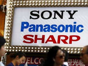 People walk past the brand logos of Japanese firms Sony, Panasonic and Sharp outside an electronic store in Tokyo June 10, 2015. REUTERS/Thomas Peter