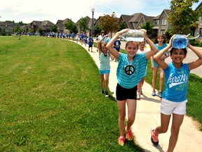 Madalyn Stachow (left) and Emma Shenouda, Grade 5 students at St. Catherine of Siena Catholic school, walk with hundreds of their peers during the first Water Walk in London Ont. June 17, 2015. CHRIS MONTANINI\LONDONER\POSTMEDIA NETWORK