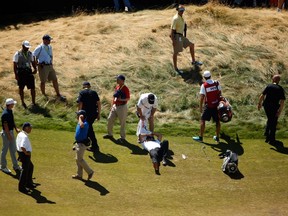 Jason Day of Australia is overcome by dizziness and lays on the ninth hole as his caddie Colin Swatton looks on during the second round of the 115th U.S. Open Championship at Chambers Bay on June 19, 2015. (Ezra Shaw/Getty Images/AFP0