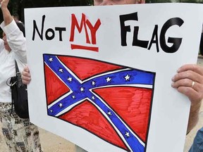 A man holds a sign up during a protest rally against the Confederate flag in Columbia, South Carolina on June 20, 2015. The racially divisive Confederate battle flag flew at full-mast despite others flying at half-staff in South Carolina after the killing of nine black people in an historic African-American church in Charleston on June 17. Dylann Roof, the 21-year-old white male suspected of carrying out the Emanuel African Episcopal Methodist Church bloodbath, was one of many southern Americans who identified with the 13-star saltire in red, white and blue. AFP PHOTO/MLADEN ANTONOV