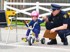 At the Optimist Club Bike Rodeo June 13, OPP Const. Kees Wijnands teaches three-year-old Tessa Bell about looking for traffic before heading out on public roads for a bike ride.  GALEN SIMMONS/MITCHELL ADVOCATE