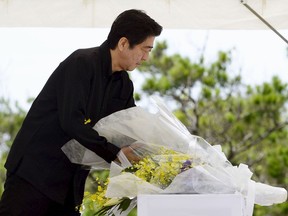 Japan's Prime Minister Shinzo Abe offers flowers for the war dead during a memorial service of the Battle of Okinawa, at the Peace Memorial Park in Itoman, on Japan's southern island of Okinawa, in this photo taken by Kyodo on June 23, 2015, to mark the 70th anniversary of the end of the battle. (REUTERS/Kyodo)