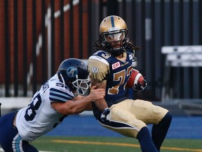 Winnipeg Blue Bombers Justin Veltung, WR eludes the tackle of Toronto Argos Jake Reinhart, LS (58) in the first half during CFL pre-season action in Toronto, Ont. at Varsity Stadium on Tuesday June 9, 2015. Jack Boland/Toronto Sun/Postmedia Network