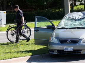 Kingston Police Const. Rick Hough removes a mangled bicycle from the scene after a male cyclist was taken to hospital with non-life threatening injuries after he was hit by a westbound vehicle at a crosswalk on Bath Road 
Ian MacAlpine/The Kingston Whig-Standard