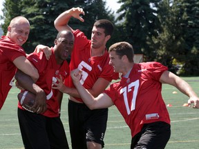 READY TO PLAY!! Ottawa RedBlacks starting QB #1 Henry Burris (second from left) gets  some playful jabbing from back-ups (from left) #4 Brock Jensen, #5 Danny O'Brien and #17 Thomas DeMarco after a morning walkthrough at Keith Harris Stadium, Wednesday, June 24, 2015. Burris and the RedBlacks later bused to Montreal where the team will open their second CFL season versus the Alouettes on Thursday night. Mike Carroccetto / Ottawa Sun
