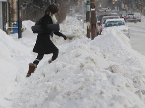 A woman climbs a pile of snow in the 1100 block of Corydon Avenue after snow clearing crews dumped a lot of snow on the sidewalk Jan 6, 2014.