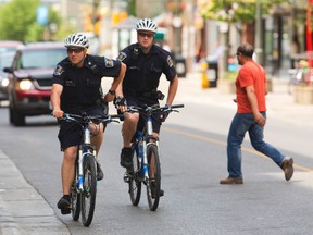 London police ride bikes along Dundas Street. The force?s rate of street checks has come under scrutiny. (MIKE HENSEN, The London Free Press)