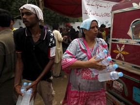 Volunteers cover their heads with water-soaked towels, to beat the heat, while distributing water bottles, outside Jinnah Postgraduate Medical Centre (JPMC) in Karachi, Pakistan, June 25, 2015. The worst heat wave to hit Pakistan's southern city of Karachi for nearly 35 years has killed more than 1,000 people, a charity said on Thursday, as morgues ran out of space and residents rushed to supply over-stretched public hospitals.  REUTERS/Akhtar Soomro