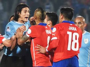 Uruguay's forward Edinson Cavani (C) argues with Chilean players after he was red-carded during their 2015 Copa America football championship quarterfinal match, in Santiago, on June 24, 2015.   AFP PHOTO / PABLO PORCIUNCULA