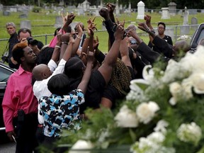 Family members raise their hands at the grave site of Ethel Lance as she is buried at the Emanuel African Methodist Episcopal Church cemetery in North Charleston, South Carolina June 25, 2015. Lance is one of the nine victims of the mass shooting at the Emanuel African Methodist Episcopal Church.  REUTERS/Brian Snyder