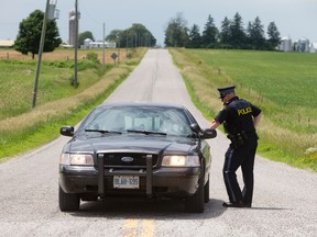 OPP police talk near the scene of a death investigation on Westminster Dr., west of Westchester Bourne, near London on Thursday. Police closed the country road between Westchester Bourne and Old Victoria Rd. to conduct an investigation. Craig Glover/The London Free Press/Postmedia Network