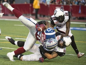 Ottawa RedBlacks' Travis Brown (43) and Jerrell Gavins bring down Alouettes' Tyrell Sutton during the CFL season-opener Thursday, June 25, 2015. (Canadian Press)