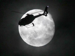 A police helicopter flies past a full moon in this April 27, 2013 file photo. (Chris Procaylo/Postmedia Network Files)