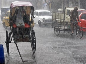 A man takes shelter inside his rickshaw during a heavy rain shower in Kolkata, India, June 25, 2015. REUTERS/Rupak De Chowdhuri