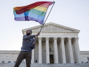 Vin Testa of Washington, D.C., waves a gay rights flag in front of the Supreme Court before a hearing about gay marriage in Washington in an April 28, 2015 file photo. The U.S. Supreme Court ruled on June 26, 2015, that the U.S. Constitution provides same-sex couples the right to marry in a historic triumph for the American gay rights movement. (REUTERS/Joshua Roberts/files)