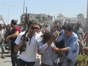 Police officers control the crowd, rear, while surrounding a man, front centre, suspected to be involved in opening fire on a beachside hotel in Sousse, Tunisia, as a woman reacts, right, on June 26, 2015. (REUTERS/Amine Ben Aziza)