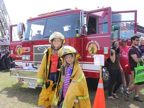 Cousins Olivia Allen, 9, and Loralei Gross, 6, take a turn dressing up as firefighters during the annual Touch the Truck event at Lavis Ball Park. (Laura Broadley/Clinton News Record)