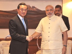Reuters file photo
Chinese Foreign Minister Wang Yi, left, shakes hands with Indian Prime Minister Narendra Modi during their meeting in New Delhi in June 2014. Wang promised to help India's economic development and emphasized that the two countries see eye to eye on most issues, playing down differences over a trade deficit and a festering border dispute.