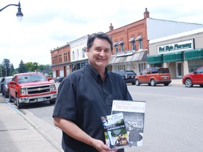 Author John Schlarbaum holds copies of his novel Lasting Impressions, which he completed the final version of recently by using comments made by readers.