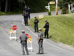 Law enforcement officers stand along County Route 41 during a search for an escaped prisoner south of Malone, N.Y., June 27, 2015. (CHRIS WATTIE/Reuters)