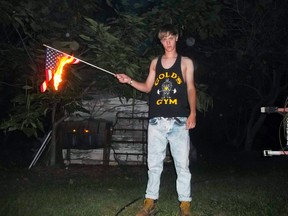 A photograph posted to a website with a racist manifesto appears to show Dylann Roof posing with a burning American flag. (Reuters/Handout)